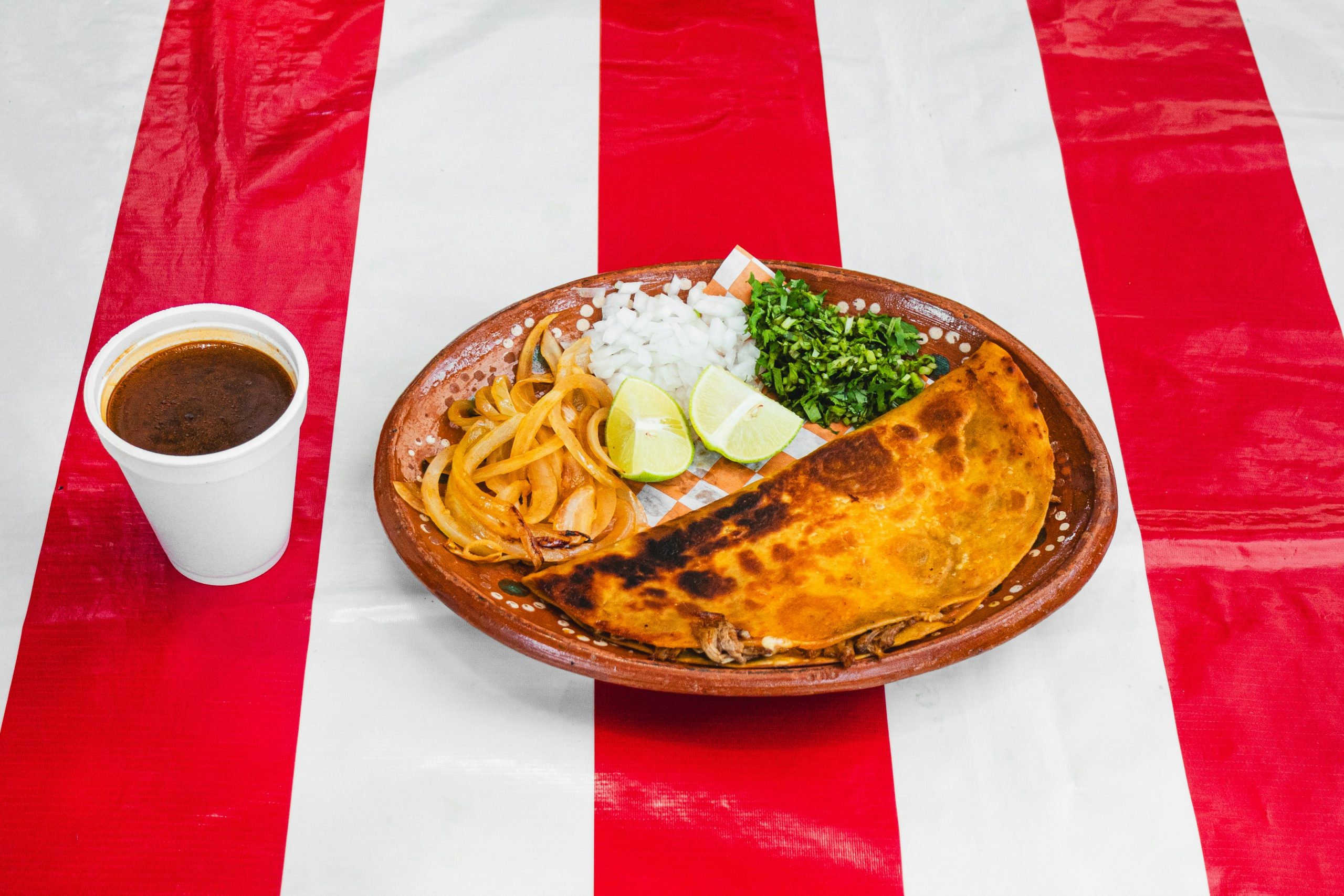 A plate of food on a red and white striped tablecloth