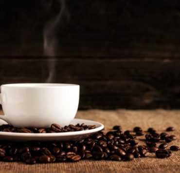white ceramic mug and saucer with coffee beans on brown textile