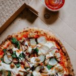 pizza with green and red vegetables on brown wooden table
