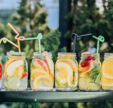 six clear glass mason jars filled with juice on black table