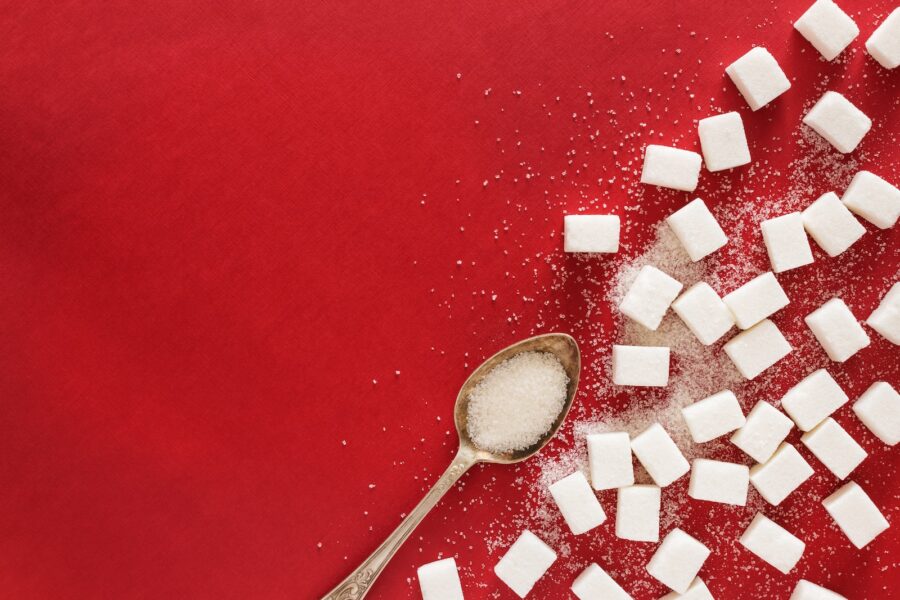 food additives, sugar cubes and a spoon on a red surface