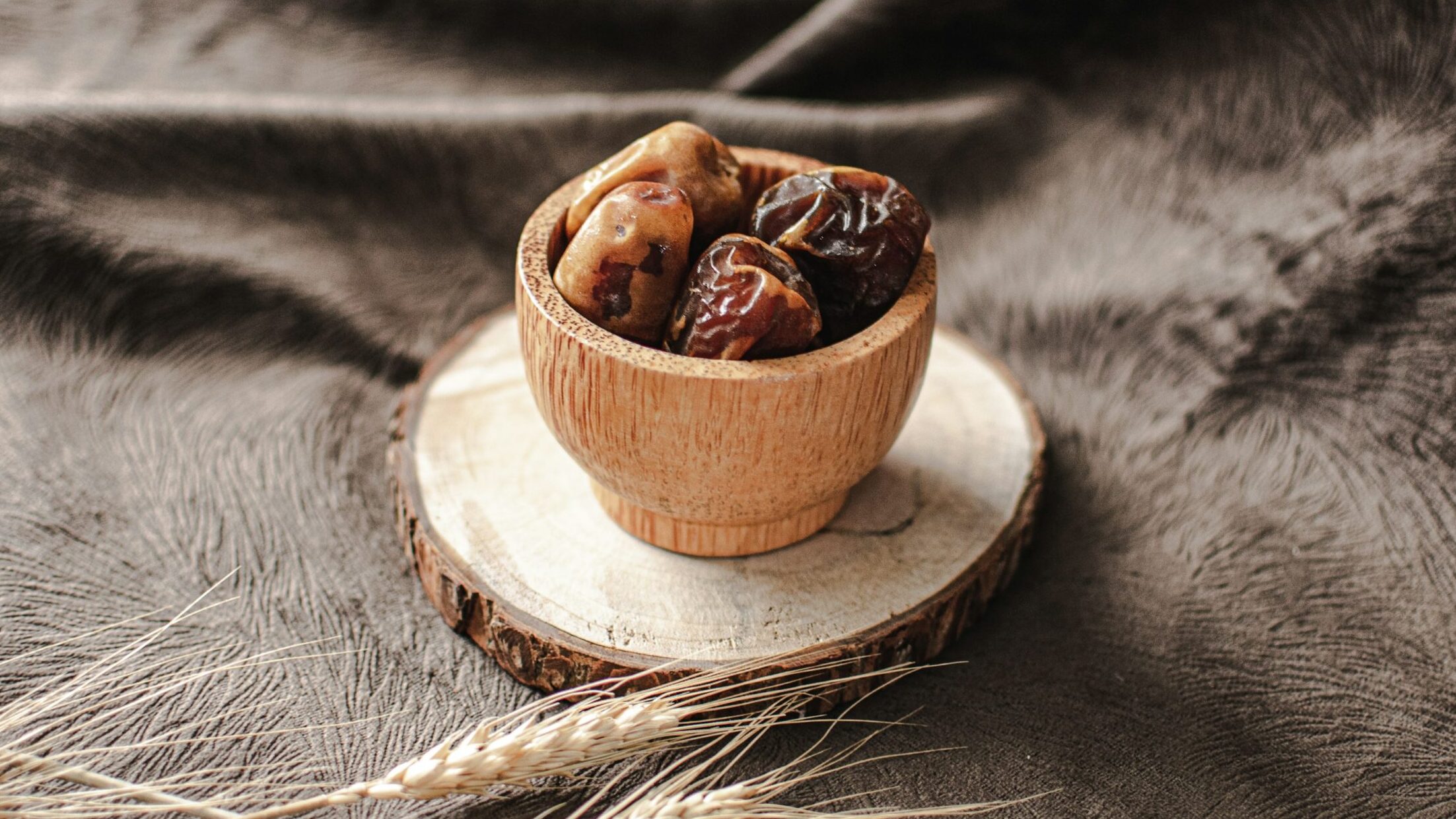 a wooden bowl filled with dates sitting on top of a table