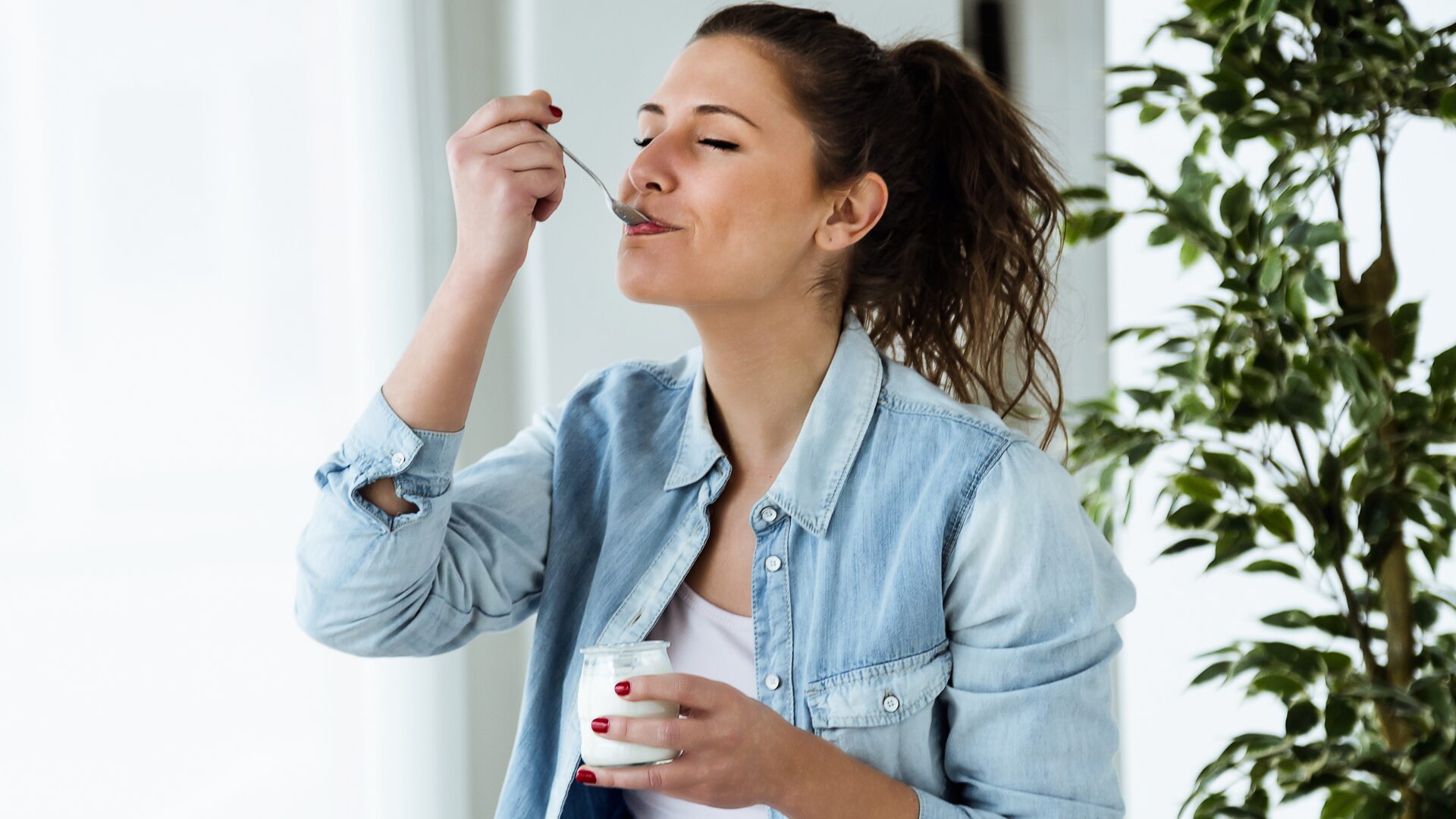 Person eating yogurt out of a jar with a spoon
