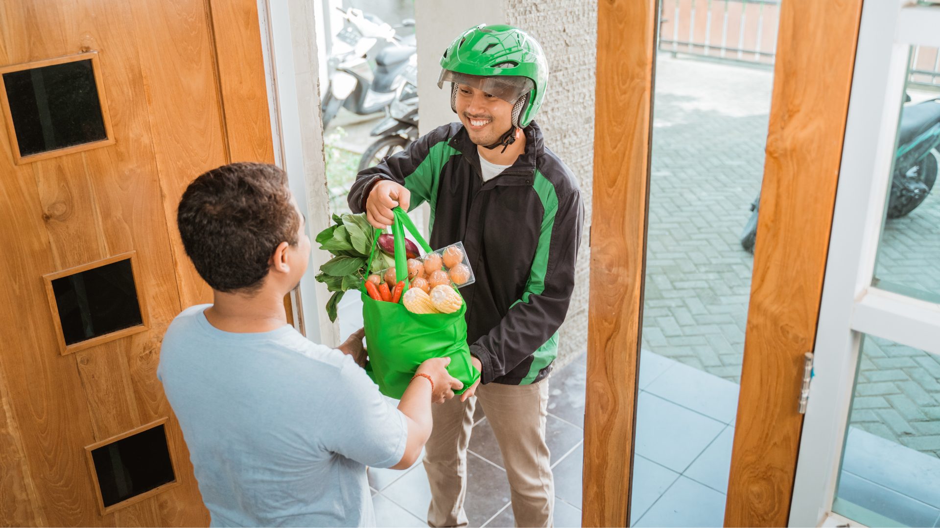 Online Grocery Sales. Delivery driver passing food to home owner.