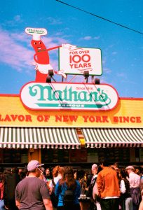 Nathan's famous hot dog stand with a crowd of people.